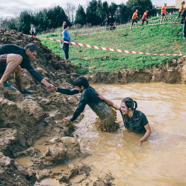 bigstock-Team-helping-to-cross-mud-pit--116872709